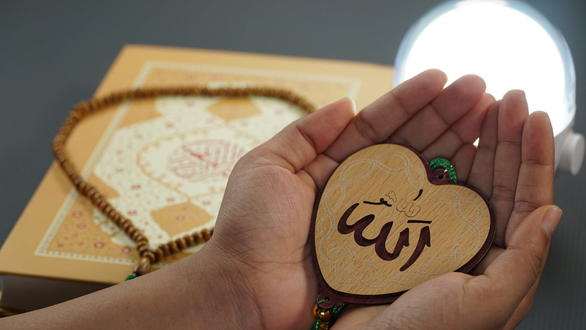 A person holding a heart-shaped wooden plaque with the word allah written on it in arabic. Gift idea: Heart-shaped plaque with "Allah" written in Arabic calligraphy. 
Islamic
Allah
Arabic calligraphy
heart
love
peace
spiritual
muslim coloring book